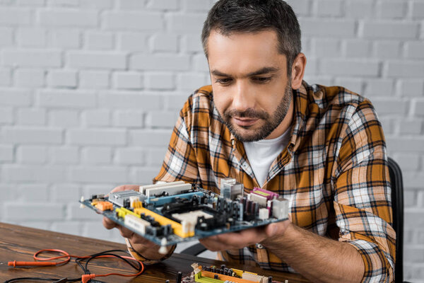 serious handsome computer engineer holding motherboard