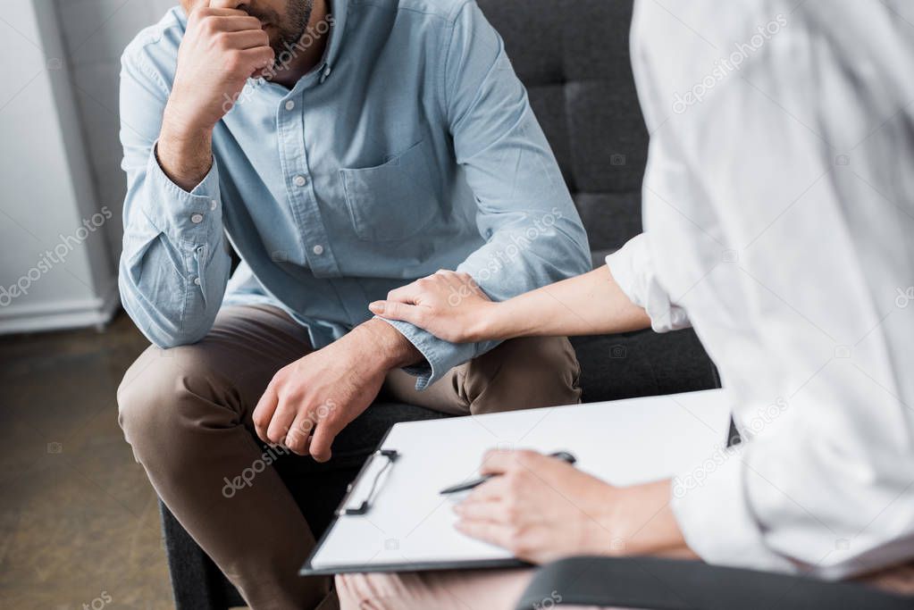 cropped shot of depressed adult man on psychologist therapy session at office