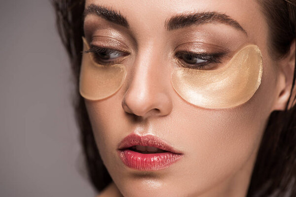 beautiful girl with collagen eye pads, isolated on grey