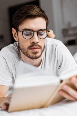 yatakta yatarken ve sabah kitap okuma gözlük yakışıklı genç adam