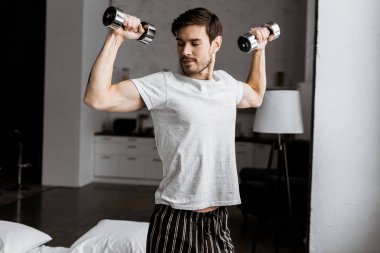 yakışıklı delikanlı dumbbells ile eğitim ve kaslara sabah seyir pijama
