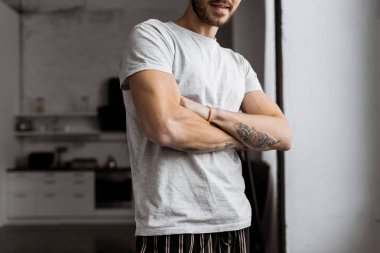 Evde duran pijama çapraz kollu yakışıklı genç adamın kırpılmış atış