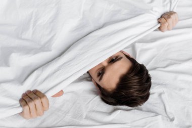 yakışıklı genç adamın evde yatakta battaniyenin altında gizleme üstten görünüm