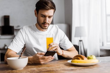 evde kahvaltı sırasında Smartphone kullanarak yakışıklı genç