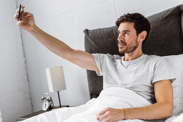 Schöner Junger Mann Macht Selfie Mit Smartphone Bett — kostenloses Stockfoto