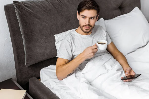 Vista Ángulo Alto Hombre Joven Sosteniendo Taza Café Uso Teléfono — Foto de stock gratuita