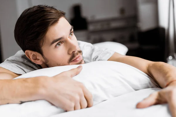 Nachdenklicher Junger Mann Der Morgens Auf Dem Bett Liegt Und — Stockfoto