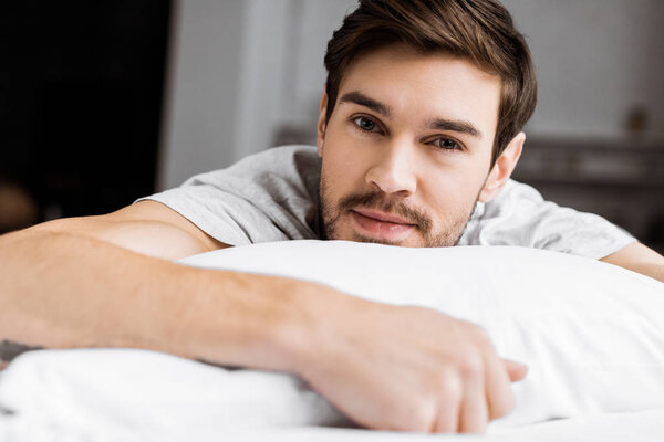 handsome young man lying on bed and looking at camera 