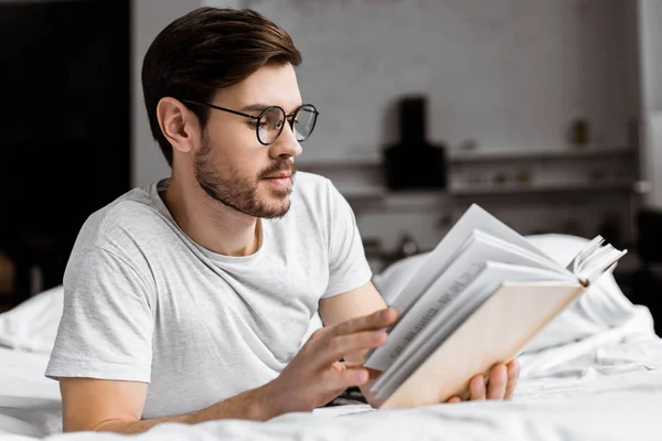 Young Man Eyeglasses Lying Bed Reading Book Morning — Stock Photo, Image