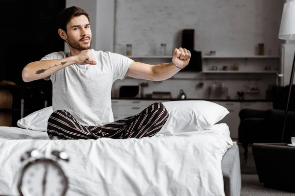 Handsome Young Man Pajamas Stretching Hands While Sitting Bed Looking — Stock Photo, Image