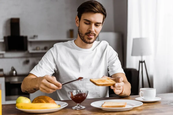 Lächelnder Junger Mann Wochenendmorgen Hause Marmelade Auf Toast Auftragen — kostenloses Stockfoto