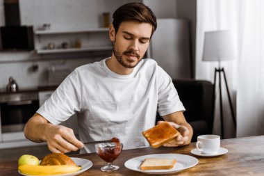 üzerine kızarmış ekmek, evde reçel uygulayarak çekici genç adam