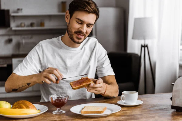 Happy Young Man Applying Jam Toast Home — Stock Photo, Image