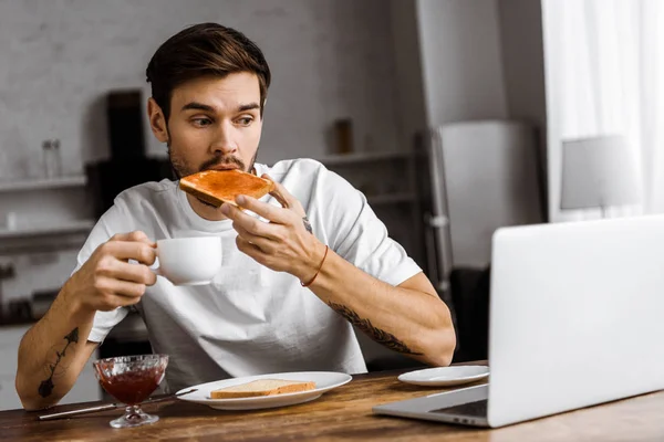 Emotionele Jonge Freelancer Eten Toast Met Jam Koffie Kijken Naar — Stockfoto