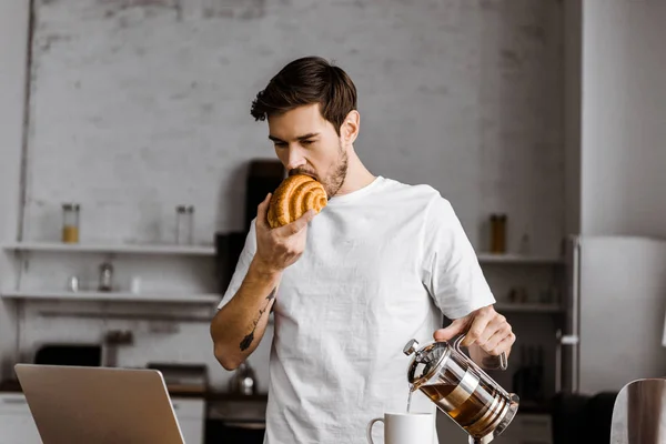 Apuesto Joven Freelancer Con Taza Croissant Portátil Trabajando Cocina Casa — Foto de stock gratis