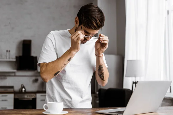 Ελκυστική Νεαρή Freelancer Γυαλιά Καφέ Και Φορητό Υπολογιστή Στην Κουζίνα — Δωρεάν Φωτογραφία