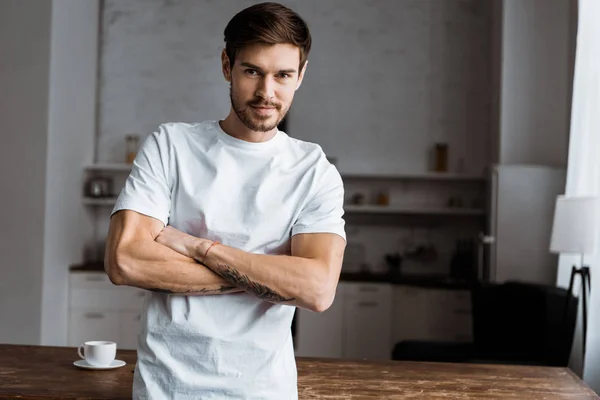 handsome young man with crossed arms looking at camera at home