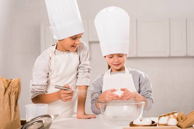 çocukların önlük ve chef şapka mutfakta masada yemek hazırlama sırasında seçici odak 