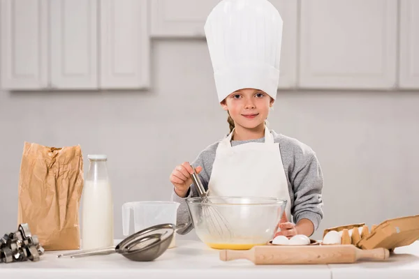 Smiling Child Chef Hat Whisking Eggs Bowl Table Kitchen — Free Stock Photo