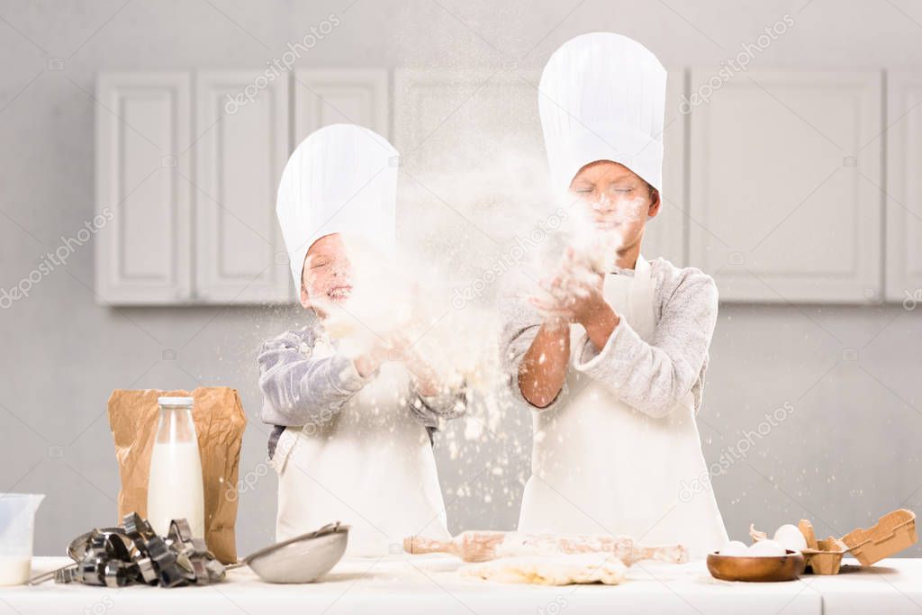 happy children in chef hats having fun with flour in kitchen 