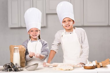 kız ve erkek kardeş eğleniyor un ile mutfak masasında chef şapka 