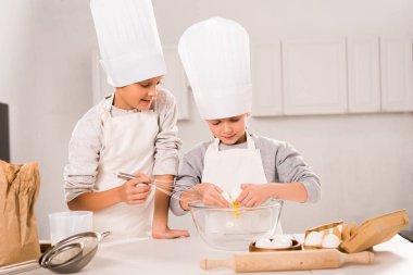 seçici odak chef şapka ve mutfak masasında kasede yumurta çırpma önlük