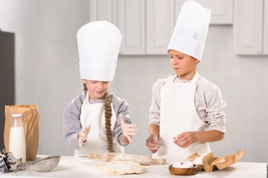 küçük çocuklarda önlük ve chef şapka hamuru oklava ile mutfak masasında yapma