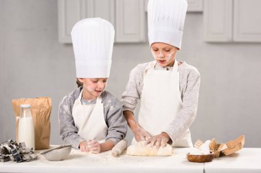 Çocuk önlük ve chef şapka hamuru oklava ile mutfak masasında yapma