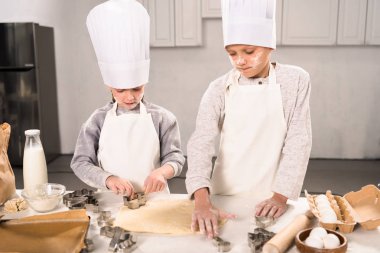 Çocuk chef şapka ve hamur mutfak masasında tanımlama bilgileri için kesmek önlük yüksek açılı görünüş