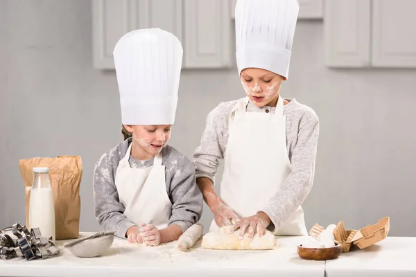 앞치마와 요리사 테이블에 핀으로 반죽을 만드는 어린이 — 스톡 사진