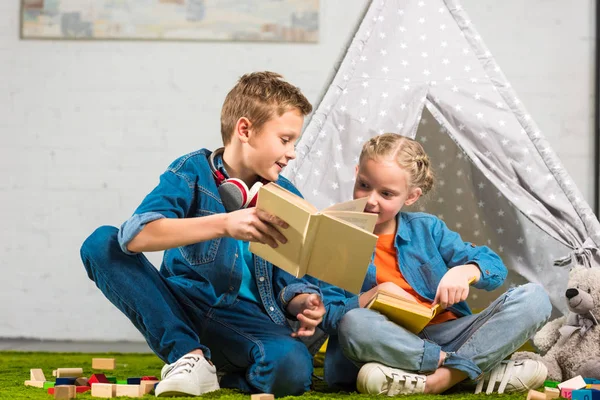 Niño Con Auriculares Sobre Cuello Mostrando Libro Hermana Pequeña Cerca — Foto de stock gratis