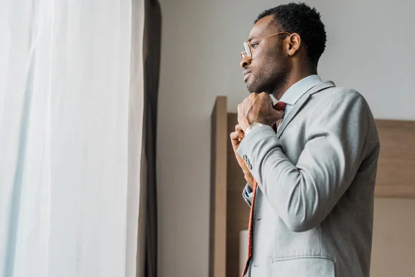 Vista Lateral Empresário Afro Americano Ajustando Gravata Vermelha Olhando Para — Fotografia de Stock Grátis