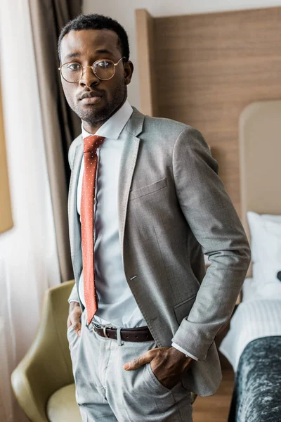 handsome businessman in gray suit and red tie posing in hotel room