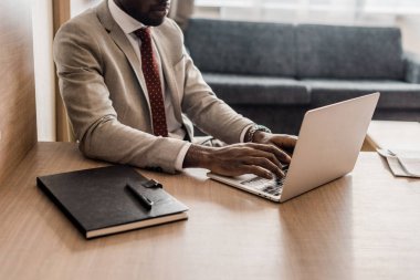 Afrika kökenli Amerikalı işadamı Laptop otel odasında çalışma görünümünü kırpılmış