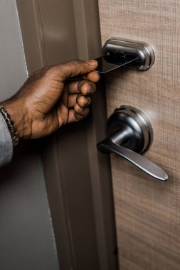 cropped view of african american man opening door with electronic key card in hotel clipart