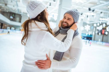 Romantik Çift buz pateni pisti üzerinde gülümseyen yan görünümü