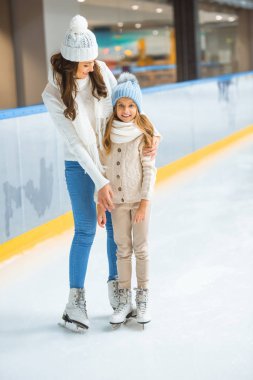 smiling kid and mother on skating rink clipart