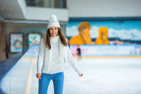 在针织毛衣上独自在溜冰场上溜冰的微笑迷人的妇女的画像 — 免费的图库照片