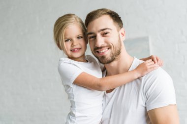 mutlu baba ve sarılma ve kameraya gülümseyen sevimli küçük kız