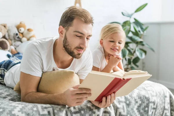 Mutlu Baba Sevimli Gülümseyen Kız Yatakta Yatarken Kitap Okuma — Stok fotoğraf
