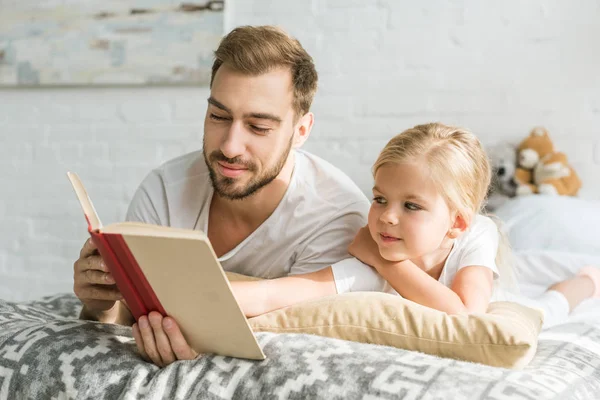 Mutlu Baba Sevimli Küçük Kız Yatakta Yatarken Kitap Okuma — Stok fotoğraf