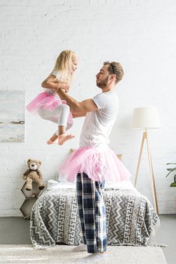 mutlu baba ve sevimli küçük kız evde dans pembe tutu etek içinde yan görünüm 
