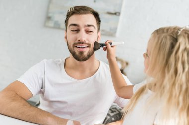 Evde baba küçük kızı gülen için makyaj uygulamak sakallı