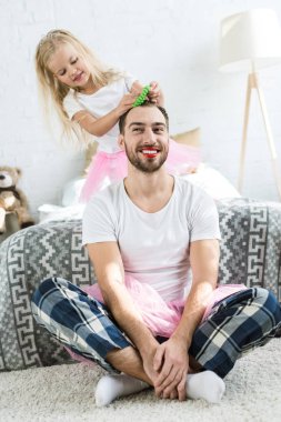 sevimli küçük kızını pembe tutu etek kırmızı ruj ile mutlu baba saç modeli yapmak  