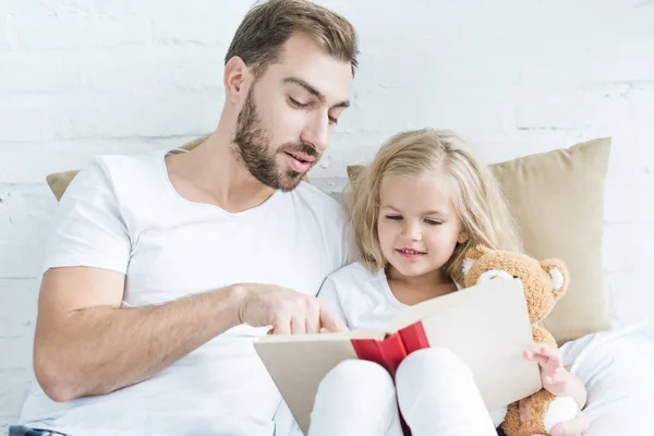 Father Cute Smiling Daughter Teddy Bear Reading Book Together Bed — Stock Photo, Image