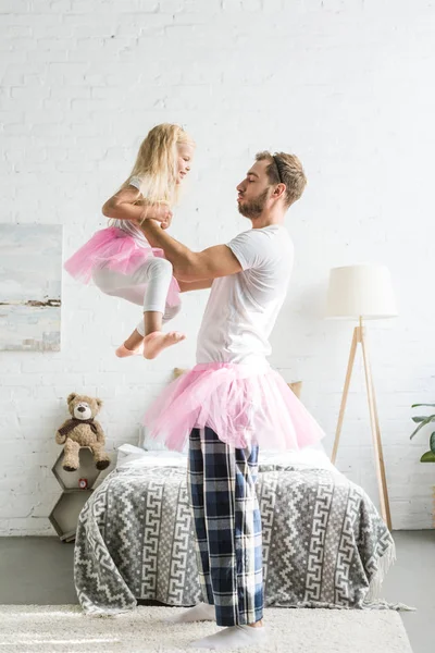 mutlu baba ve sevimli küçük kız evde dans pembe tutu etek içinde yan görünüm 