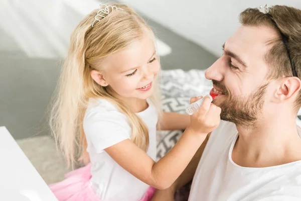 幸せな父の自宅に化粧を適用する愛らしい小さな娘  — 無料ストックフォト