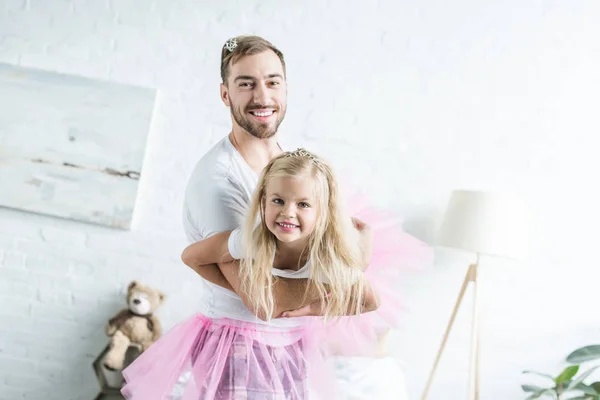 快乐的父亲和可爱的小女儿在粉红色的 Tutu 裙子跳舞和微笑在相机 — 免费的图库照片