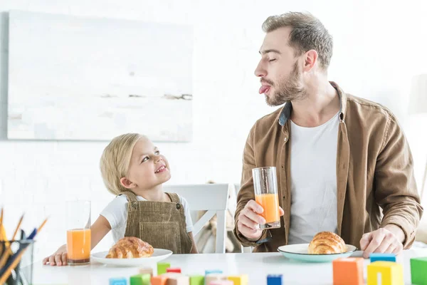 Father Showing Tongue Out Little Daughter While Having Breakfast Together — Stock Photo, Image
