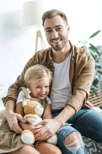 幸せな父と娘は家で一緒に座っているクマのぬいぐるみ  — 無料ストックフォト
